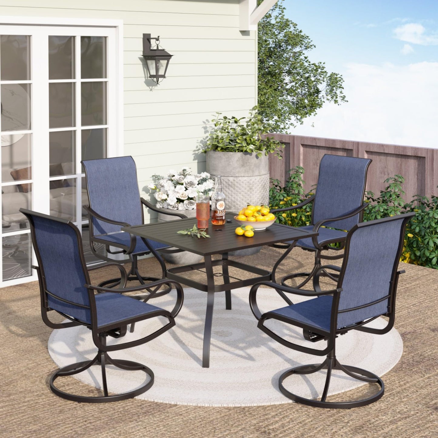 Outdoor patio set with four blue chairs and a table on a patio.