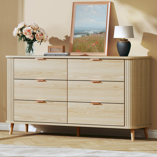Wooden dresser with decorative items on top against a beige wall.