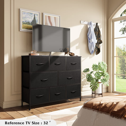 Black dresser with a TV mounted above it in a room with a window and plant.