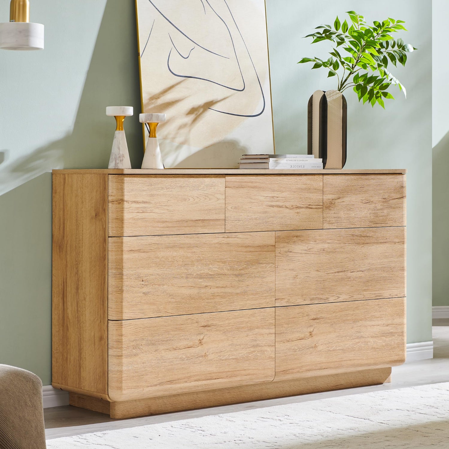 Wooden sideboard with decorative items in a room with a light green wall and plant.