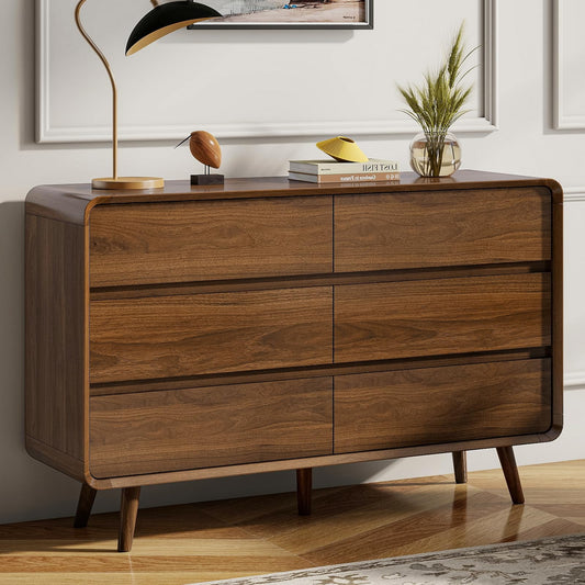 Wooden dresser with decorative items on top against a neutral wall.